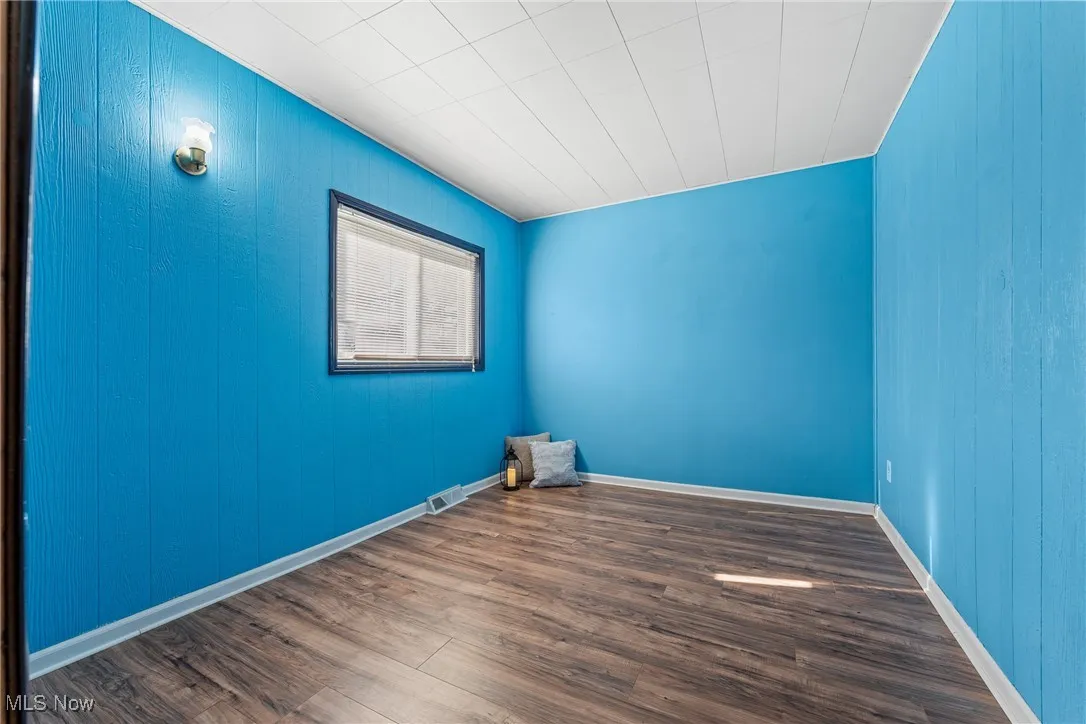 Spare room with dark wood-style flooring and wood walls