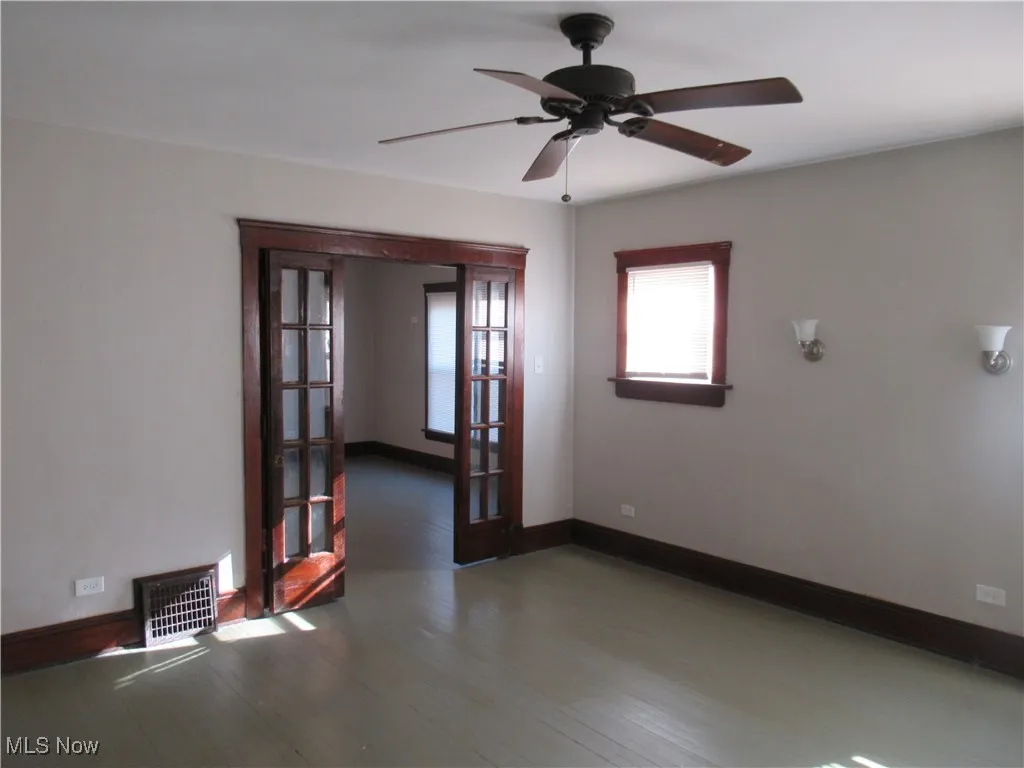 Unfurnished room with french doors, a ceiling fan, and wood finished floors