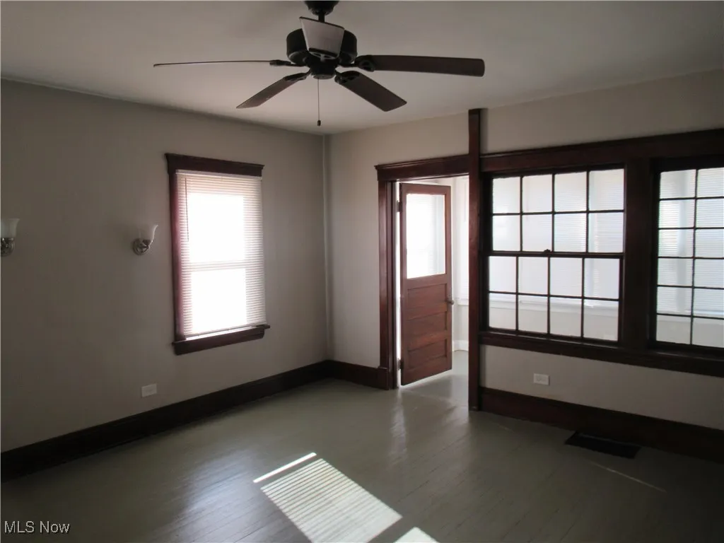 Empty room with a ceiling fan and dark wood-style flooring
