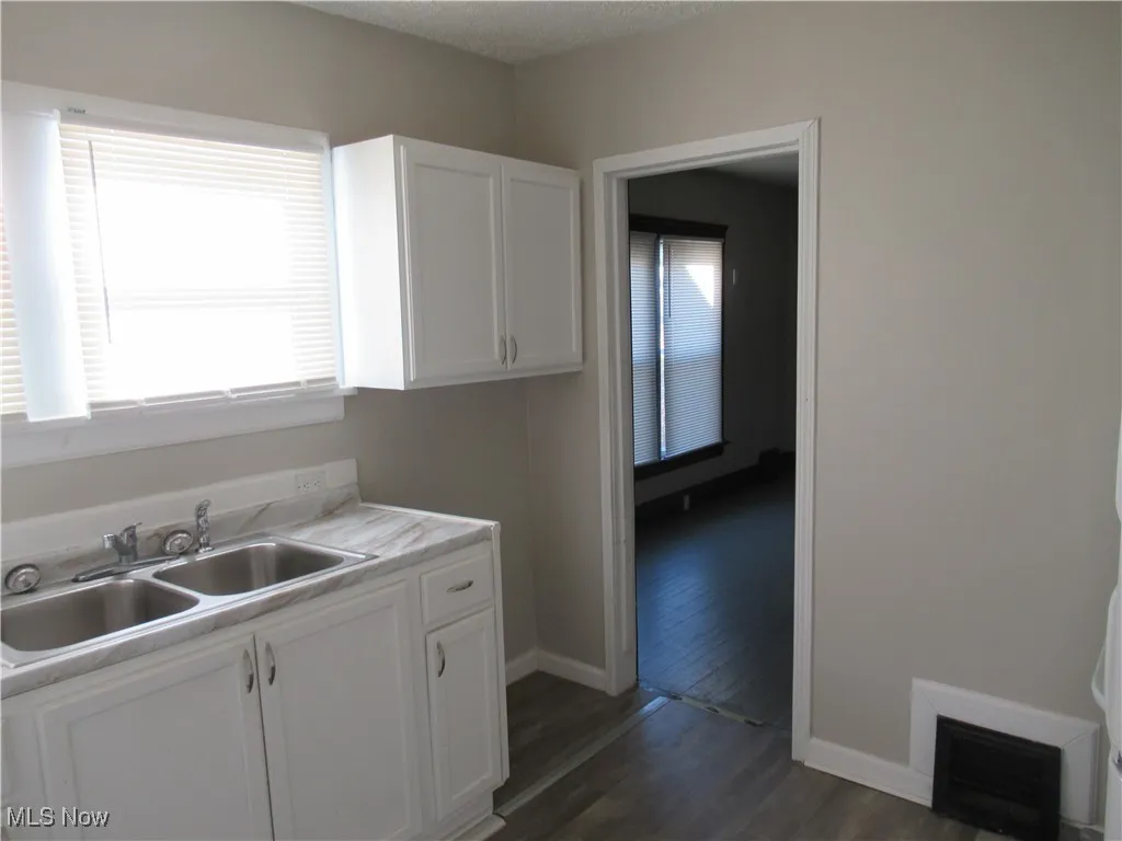 Kitchen with white cabinets, light countertops, dark wood-type flooring, and a textured ceiling
