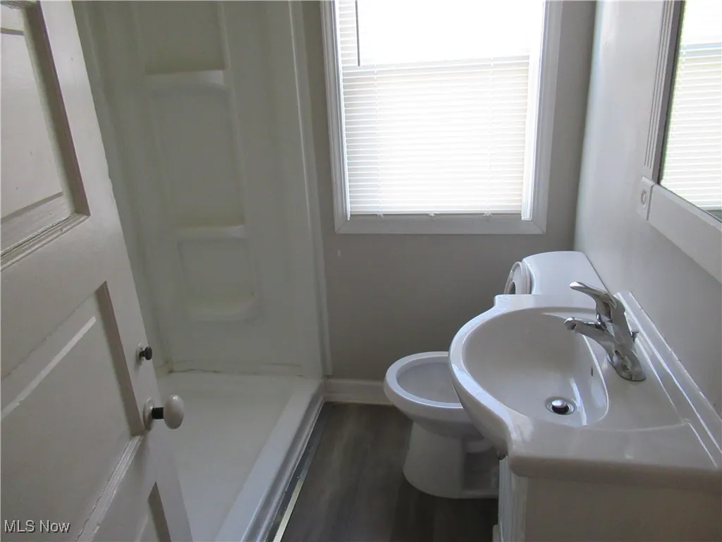 Full bath featuring a shower stall, vanity, and dark wood-type flooring