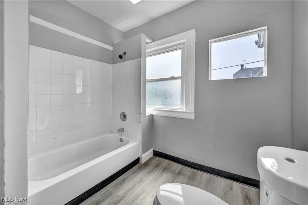 Bathroom featuring tiled shower / bath, hardwood / wood-style flooring, and toilet