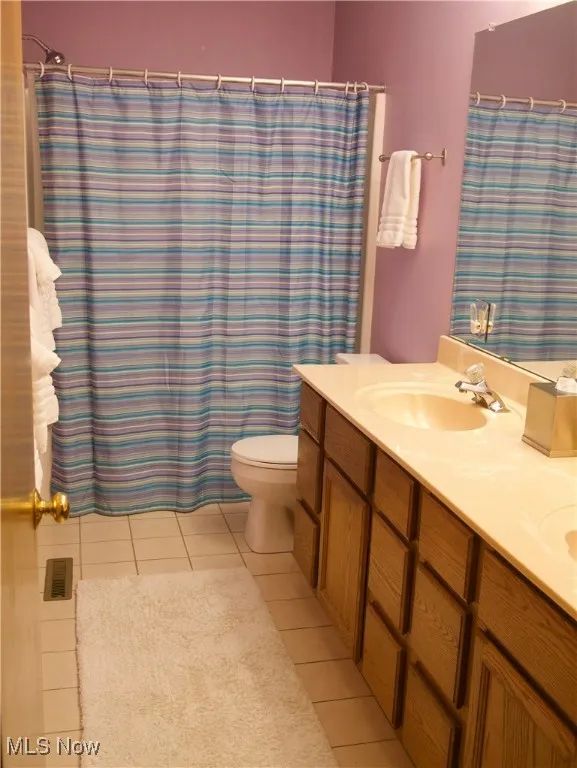 Full bath featuring double vanity, curtained shower, and light tile patterned floors
