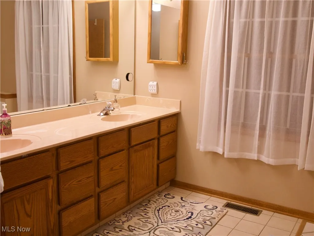 Full bathroom featuring double vanity and light tile patterned floors
