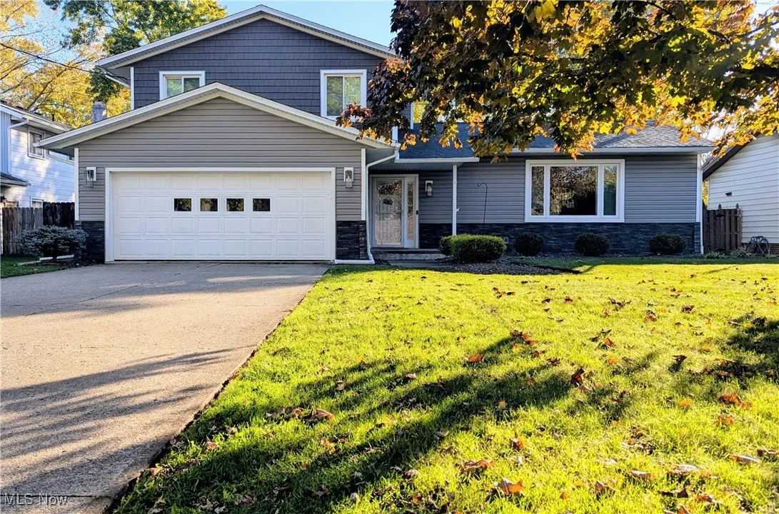 View of Front of Split Level with Brick and Newer Grey Vinyl Siding, extra Parking on side of Driveway and for turn around