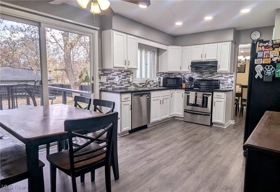 View of Eat In Kitchen with Newer LVT Flooring, Stainless Steel Dishwasher and Range, White Cabinets and Sliders leading out to the Two Tier Deck