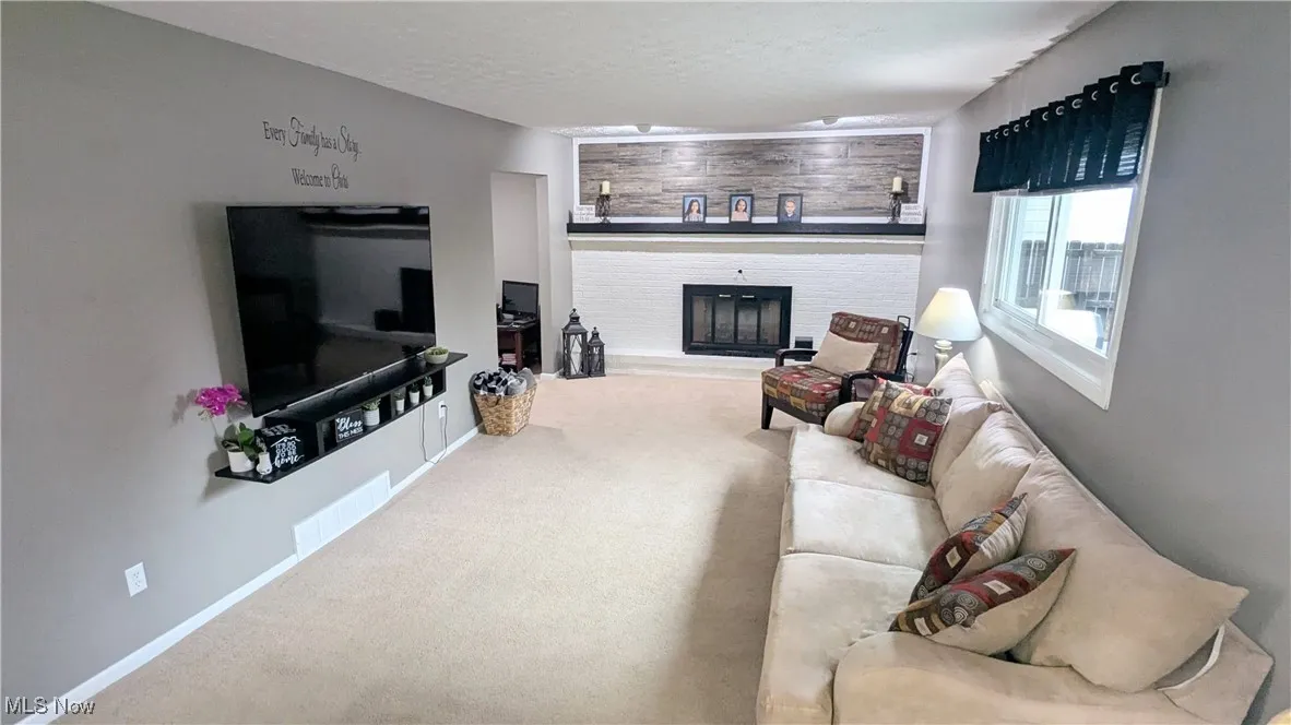 View of Family Room with Updated Fireplace with Mantel, Carpeting, Window Treatments and Modern Paint