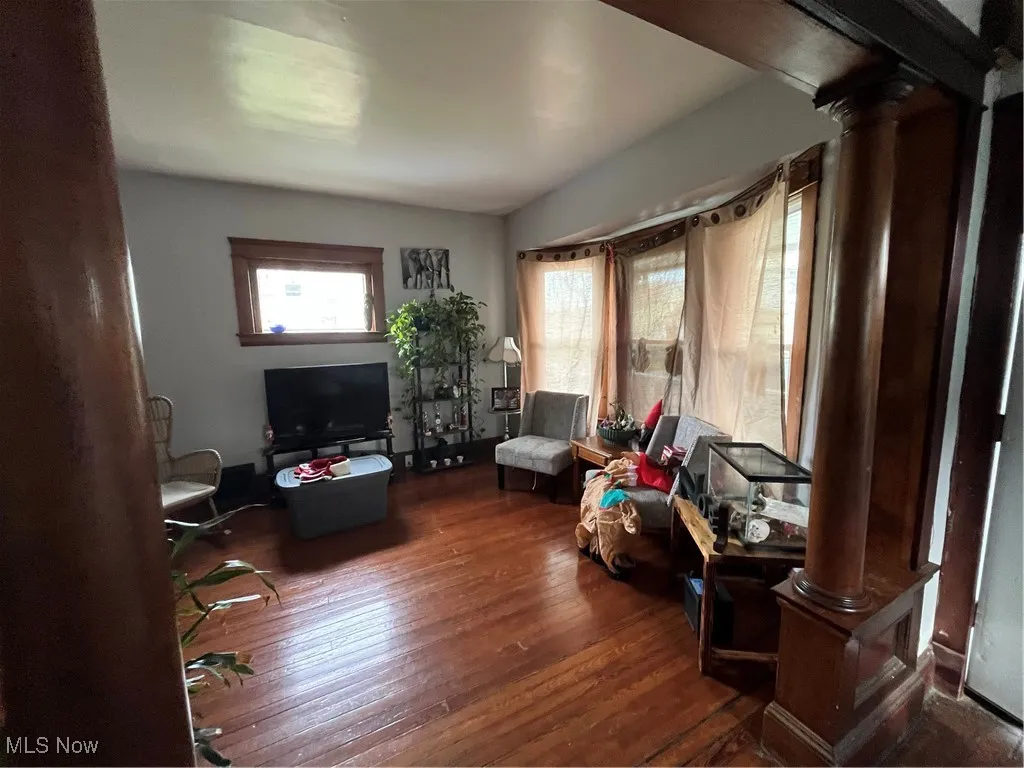 Sitting room featuring decorative columns and dark wood-style flooring