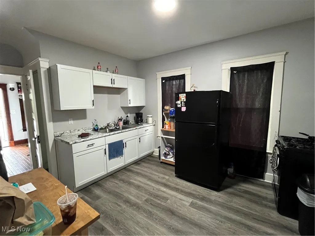Kitchen with fridge, light countertops, white cabinetry, range, and dark wood-type flooring