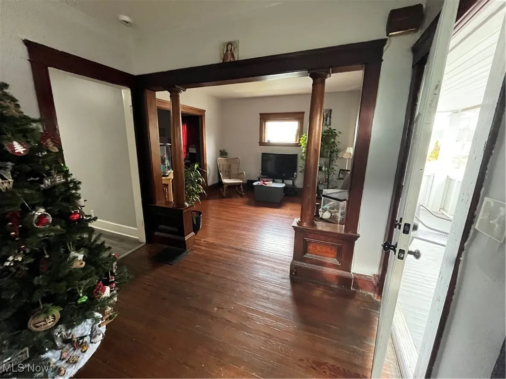 Foyer featuring ornate columns and dark wood finished floors