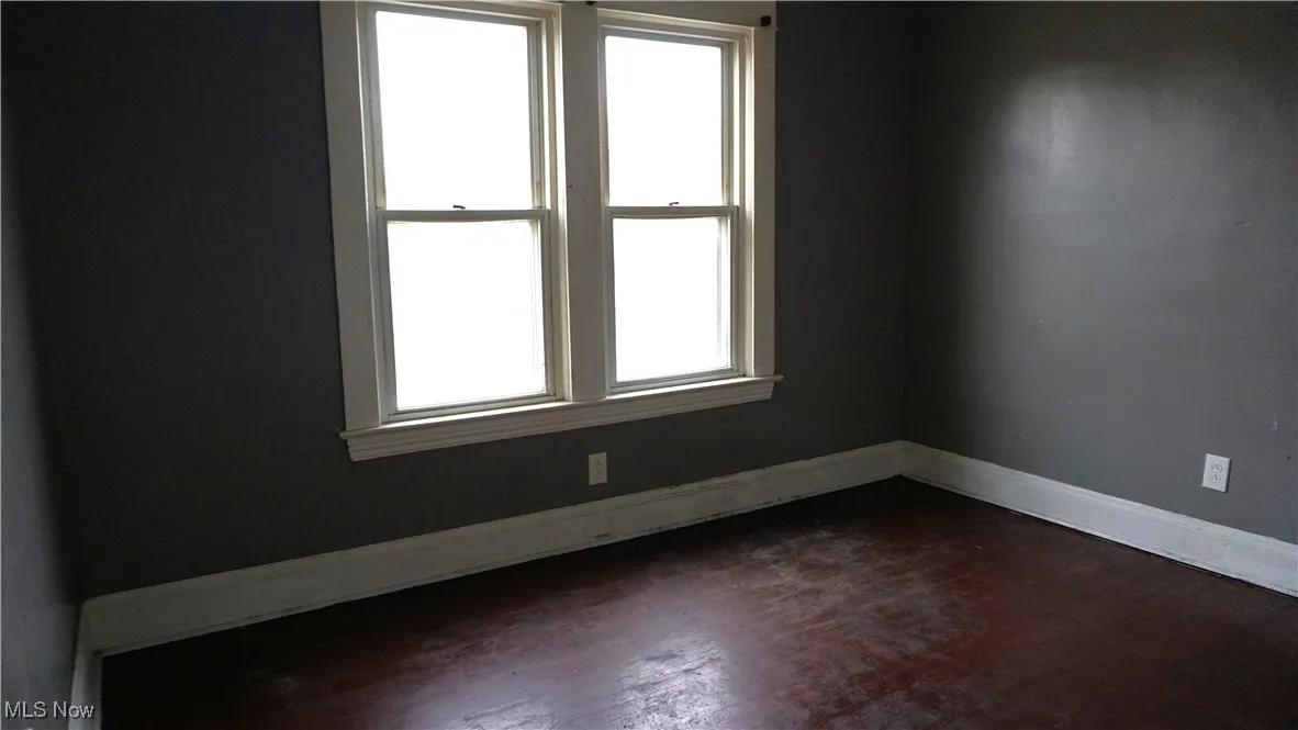 Empty room with baseboards and dark wood finished floors