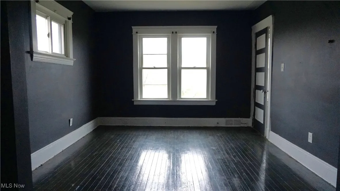 Empty room with baseboards and dark wood finished floors