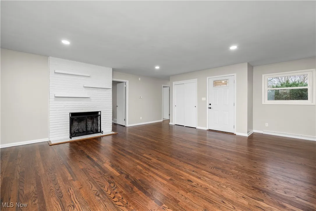 Unfurnished living room featuring recessed lighting, dark wood-style flooring, and a fireplace