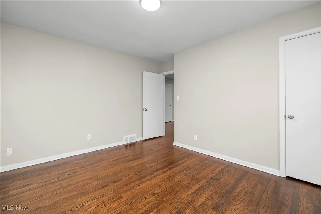 Unfurnished bedroom featuring dark wood finished floors and baseboards