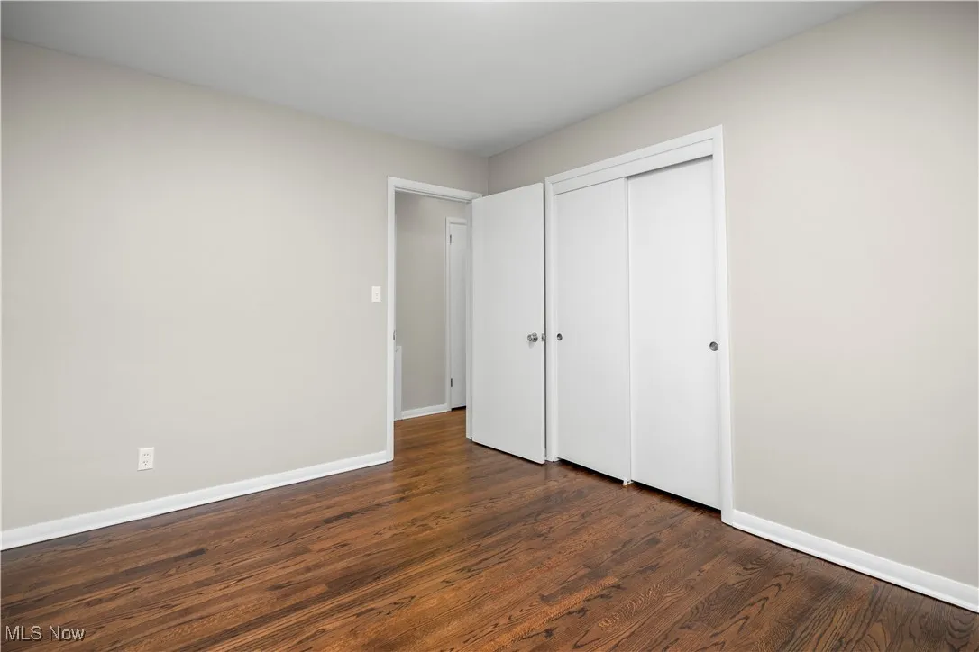 Unfurnished bedroom featuring dark wood-style flooring and a closet