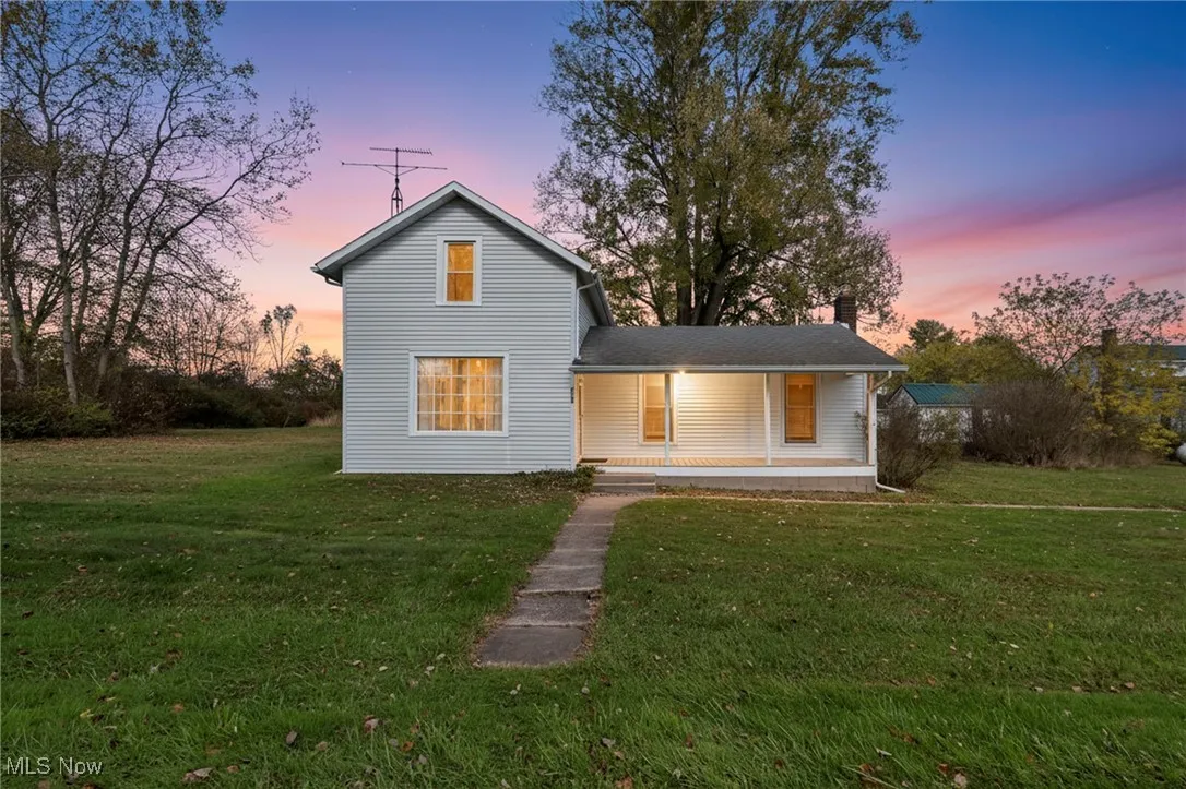 Back of house with covered porch, a lawn, and a chimney