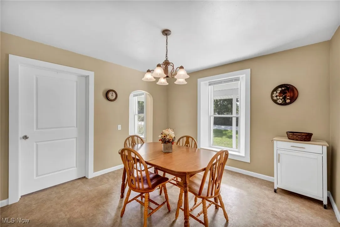 Dining space featuring arched walkways, light colored carpet, and a chandelier