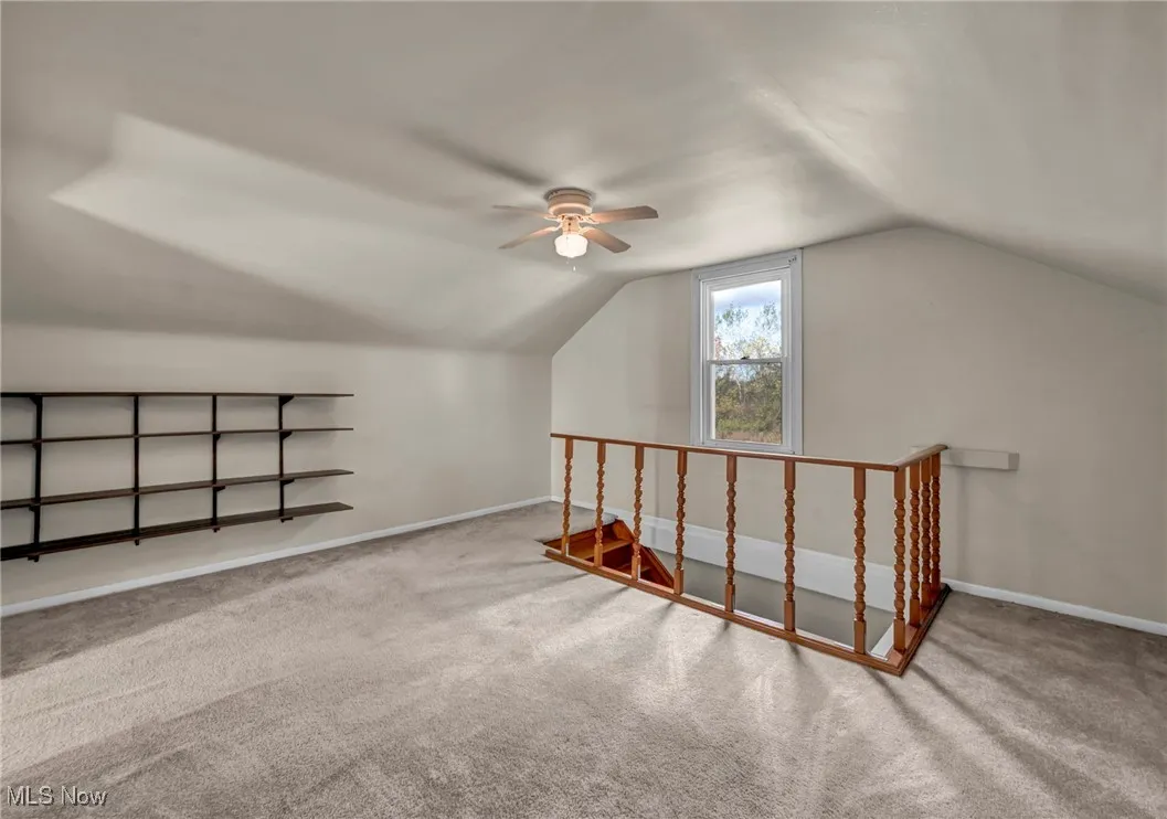 Bonus room with vaulted ceiling, carpet flooring, and a ceiling fan
