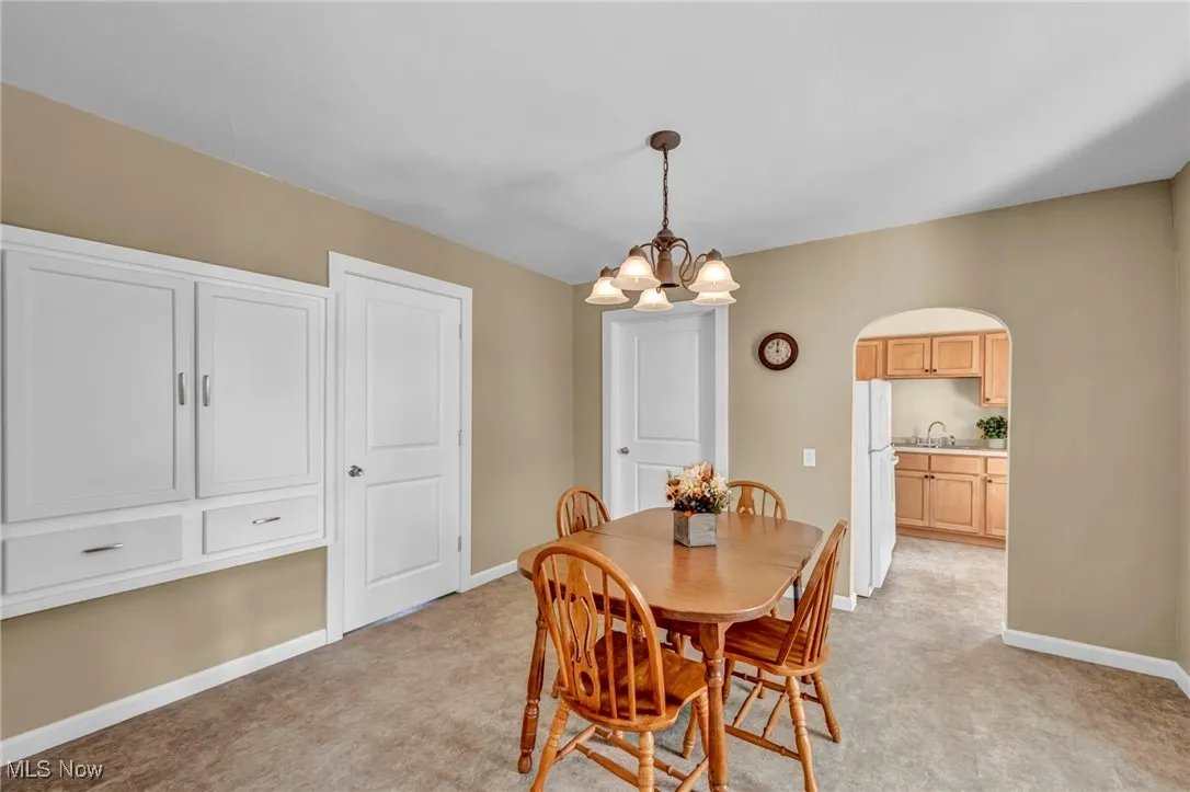 Dining room featuring a chandelier, light colored carpet, and arched walkways