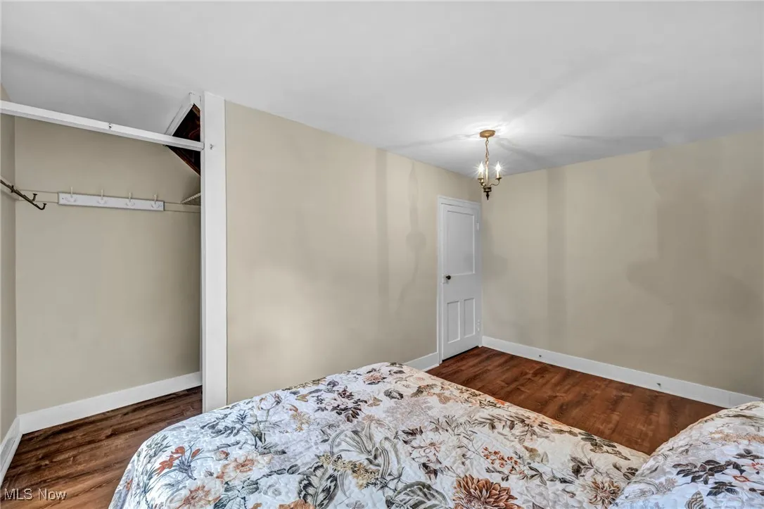 Bedroom featuring dark wood-style floors, a chandelier, and a closet