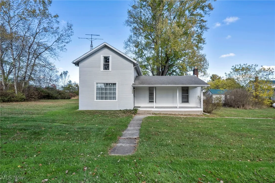 Back of house featuring a porch, a yard, and a chimney
