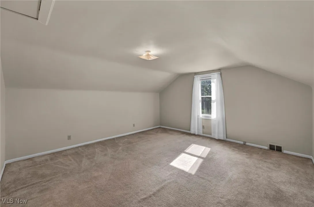 Bonus room featuring lofted ceiling and carpet flooring