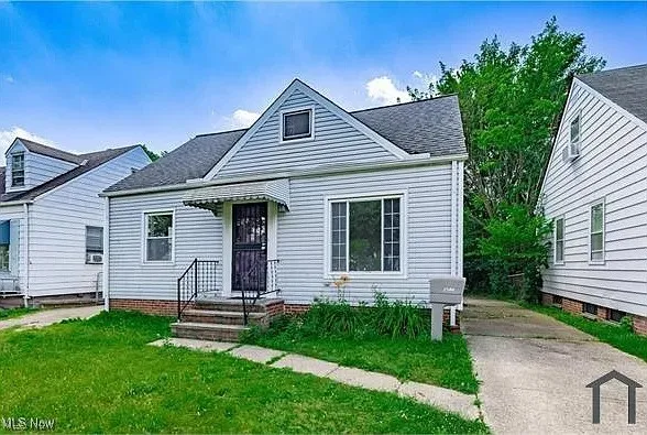 Bungalow-style home with a front yard and roof with shingles