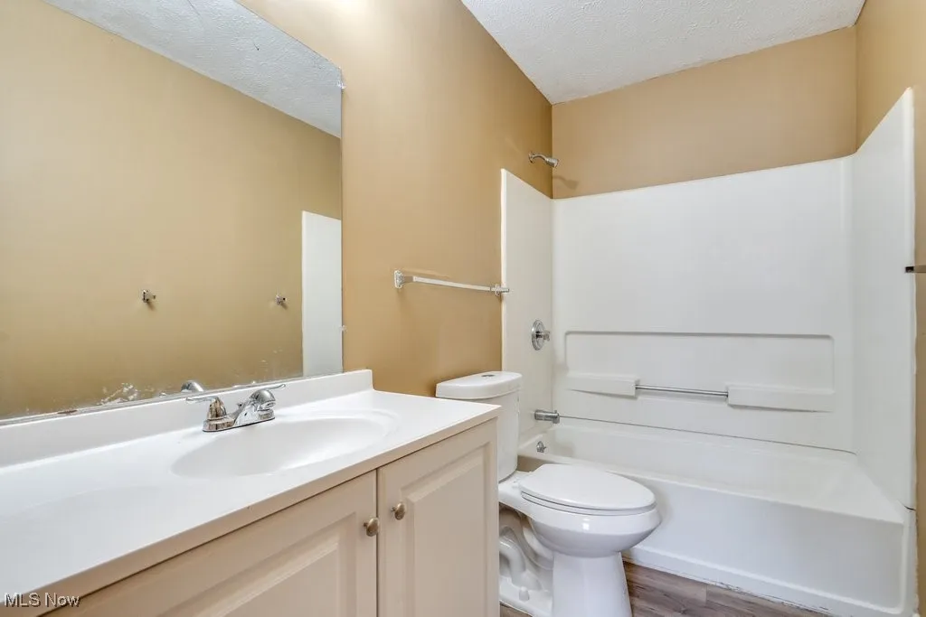 Bathroom featuring vanity, a textured ceiling, shower / tub combination, and wood finished floors