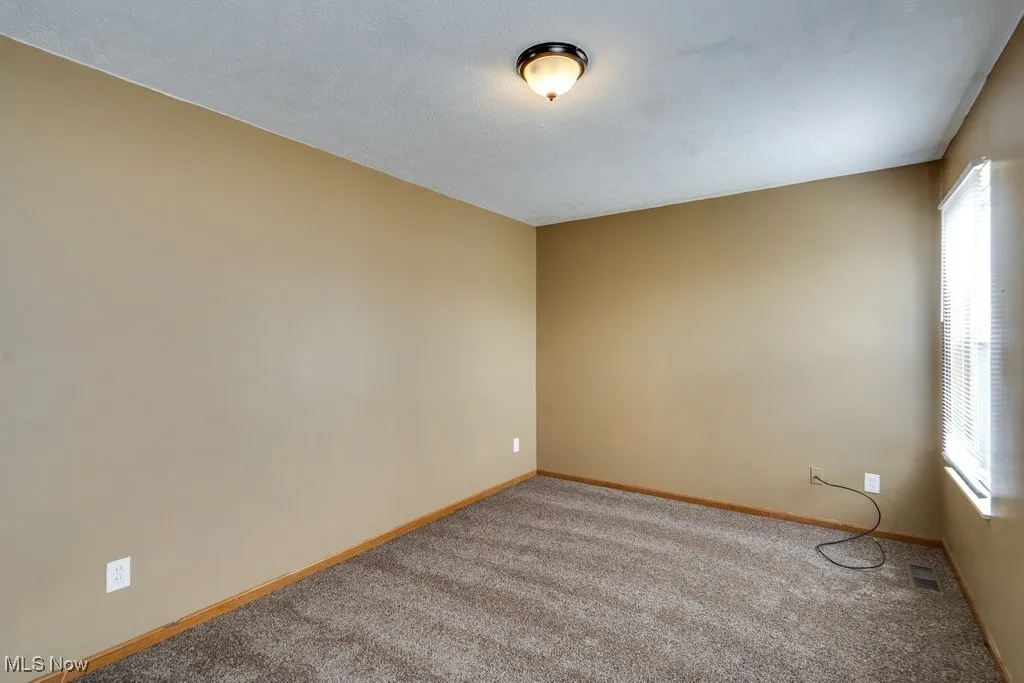 Carpeted empty room with baseboards and a textured ceiling