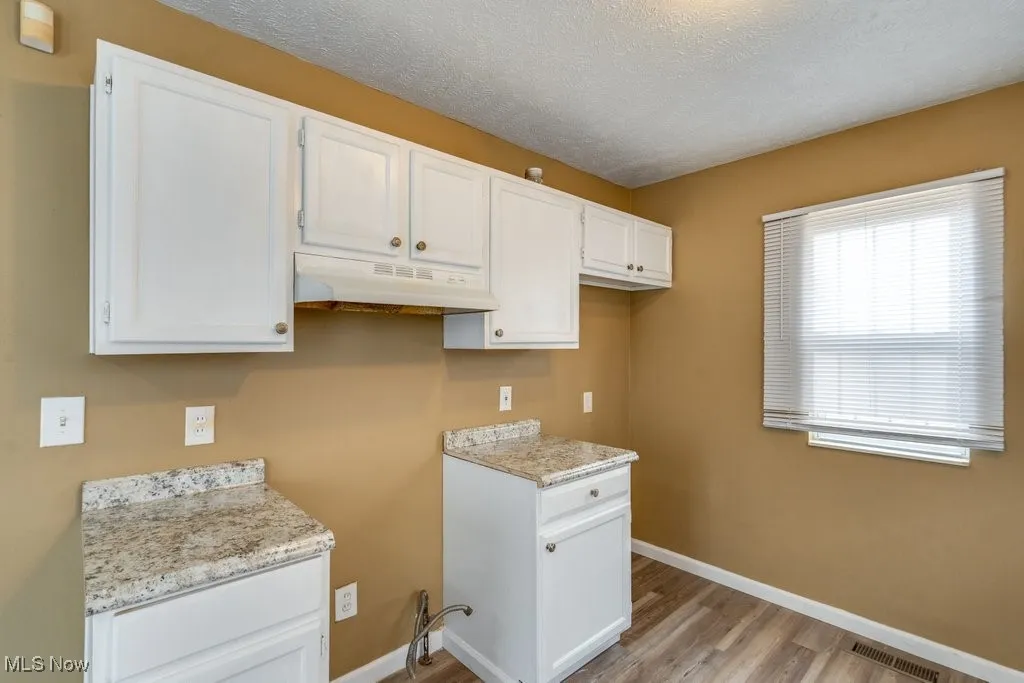 Laundry area featuring a textured ceiling and light wood-type flooring