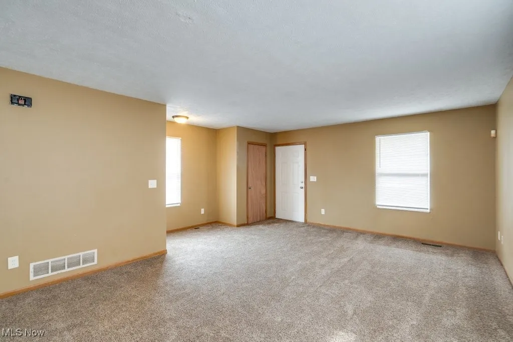 Unfurnished room with light carpet and a textured ceiling
