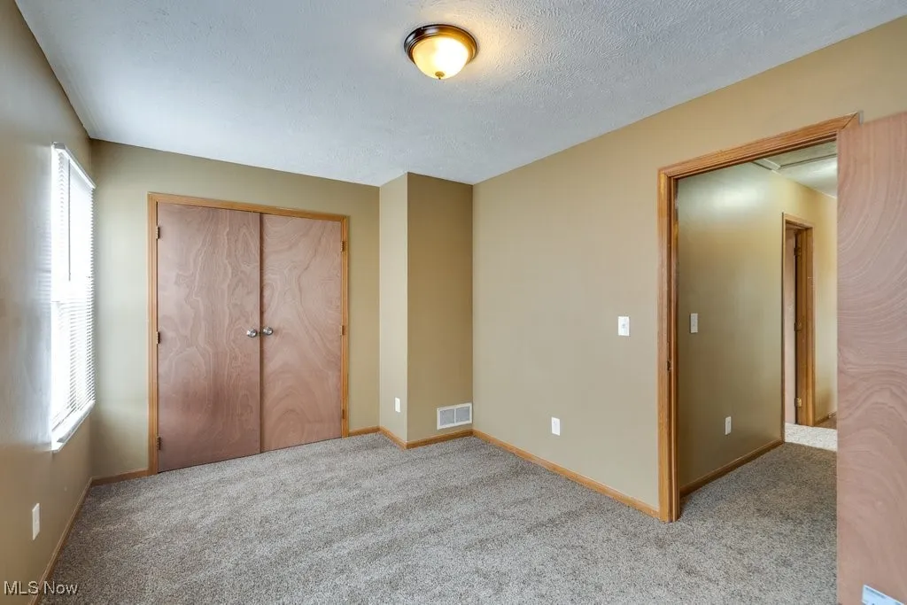 Unfurnished bedroom featuring carpet, a textured ceiling, and a closet