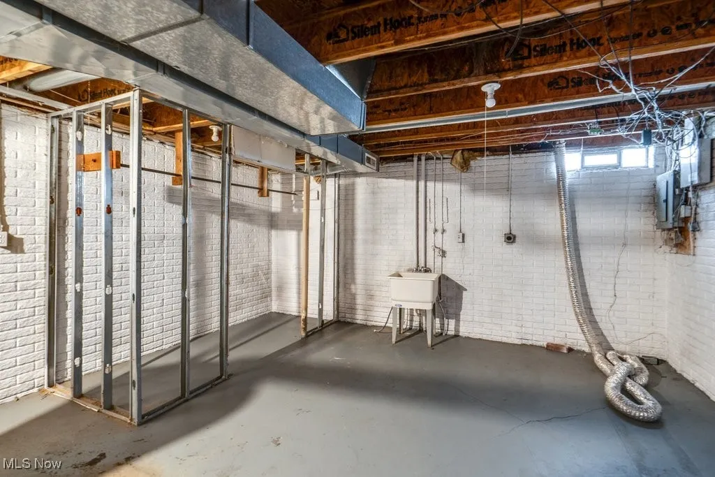 Unfinished basement featuring a sink and electric panel