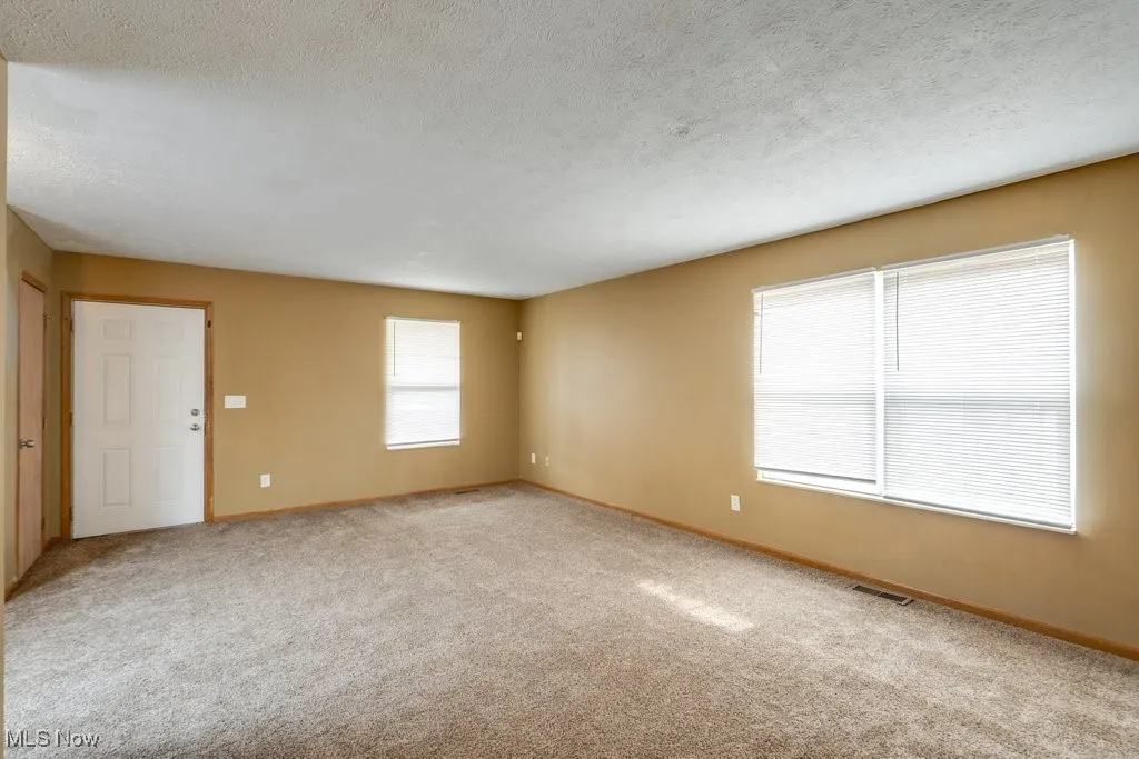 Unfurnished room featuring a textured ceiling and light colored carpet