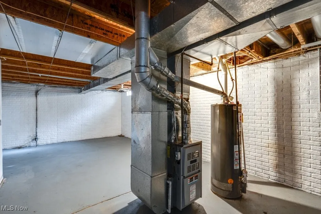 Unfinished below grade area featuring gas water heater and heating unit