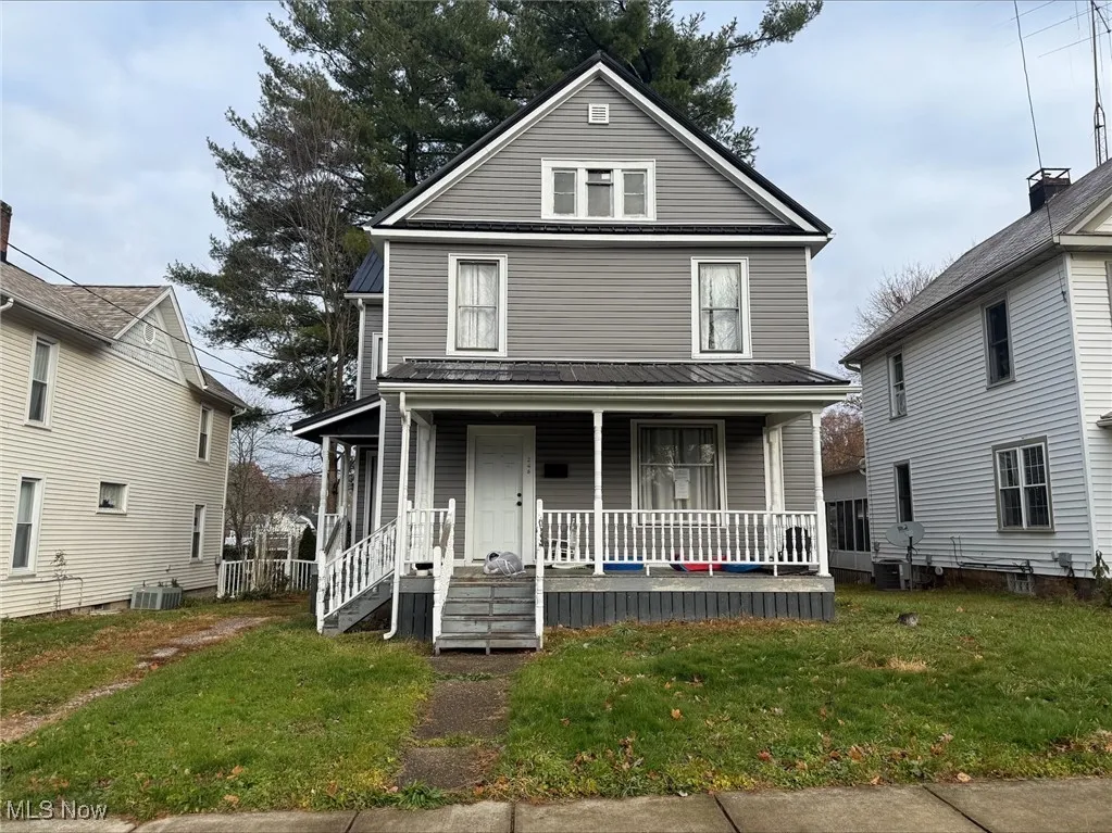 Traditional style home with a porch, a front yard, and a metal roof