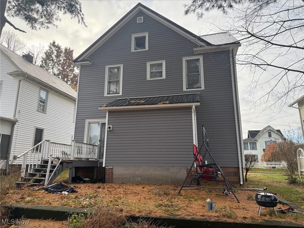 Back of house featuring a metal roof, an outdoor fire pit, stairway, and a deck