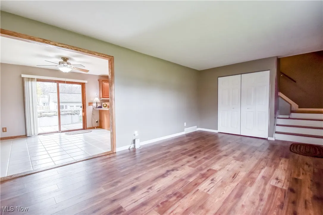 Unfurnished living room featuring stairs, light wood finished floors, and a ceiling fan
