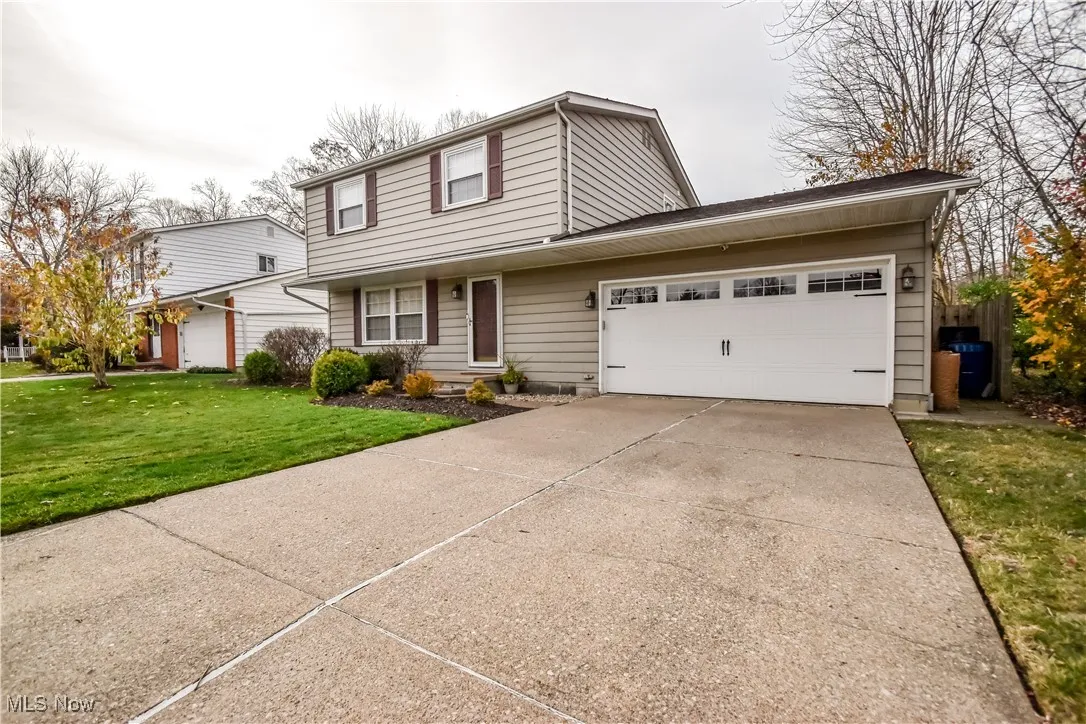 Traditional-style house featuring concrete driveway, a front yard, and an attached garage