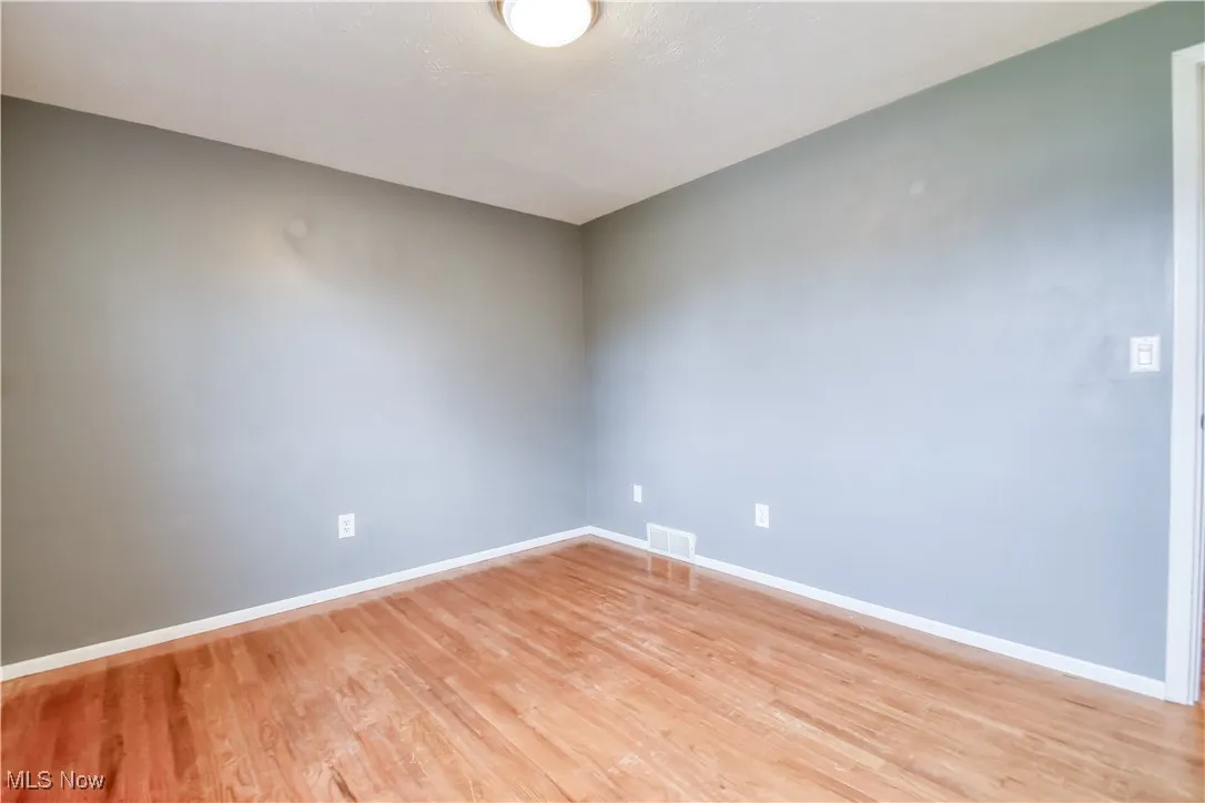 Empty room featuring baseboards and light wood-style flooring