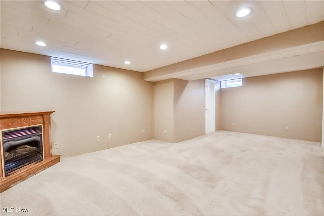 Basement featuring a fireplace with raised hearth, recessed lighting, and carpet floors