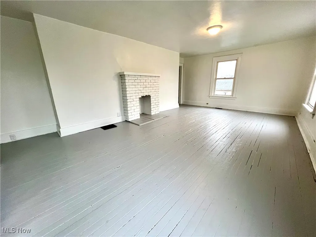 Unfurnished living room featuring a brick fireplace and hardwood / wood-style flooring