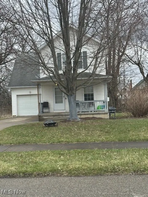 View of front facade with a porch, a front yard, a garage, concrete driveway, and a shingled roof