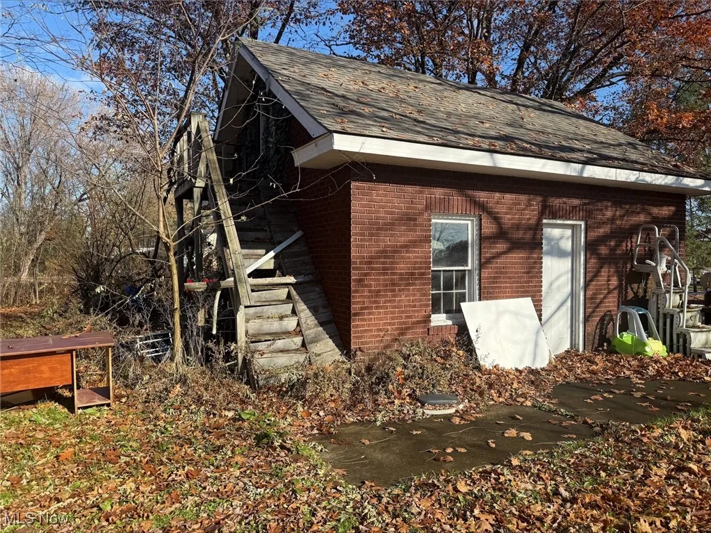 View of side of home with brick siding and roof with shingles