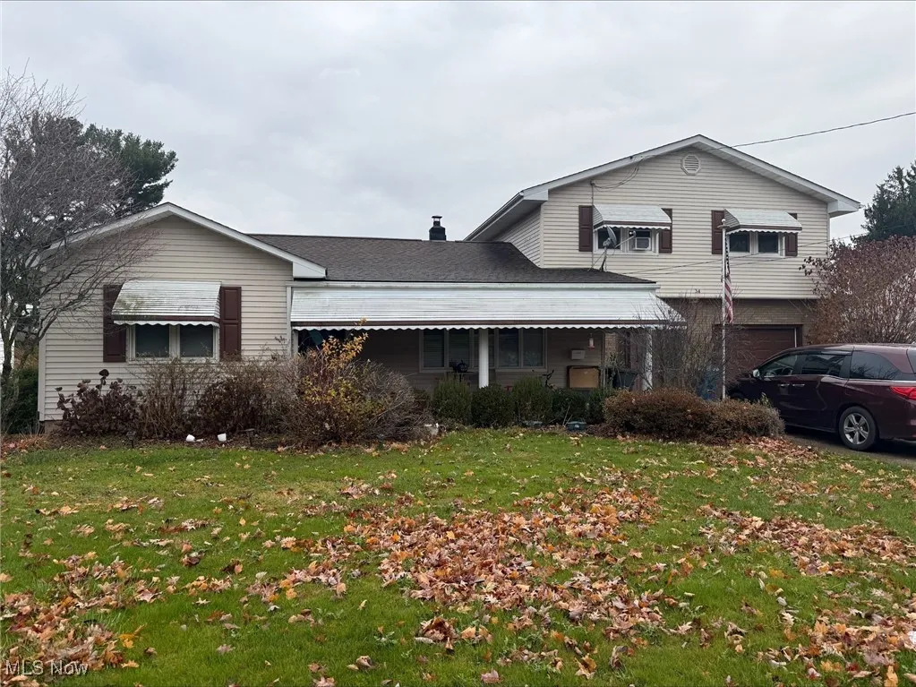 View of front facade with a front lawn, an attached garage, and a chimney