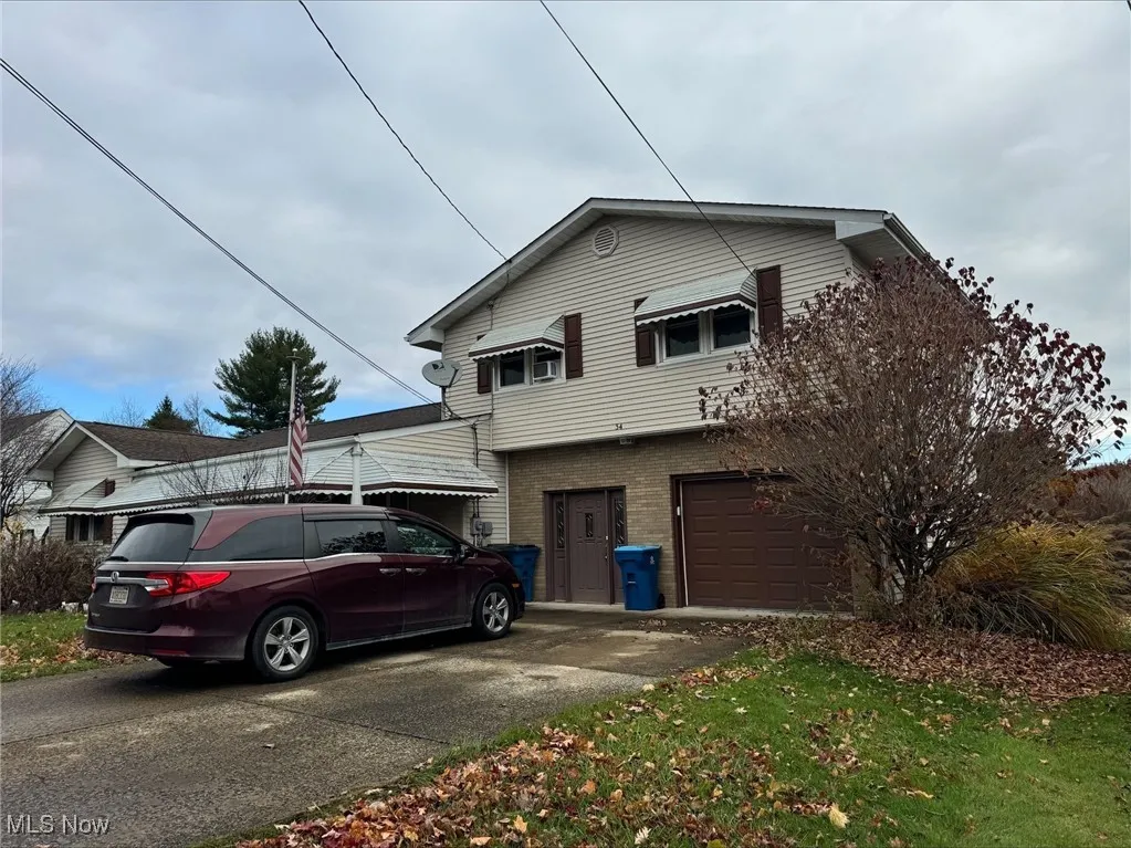 View of front facade with brick siding, driveway, and an attached garage