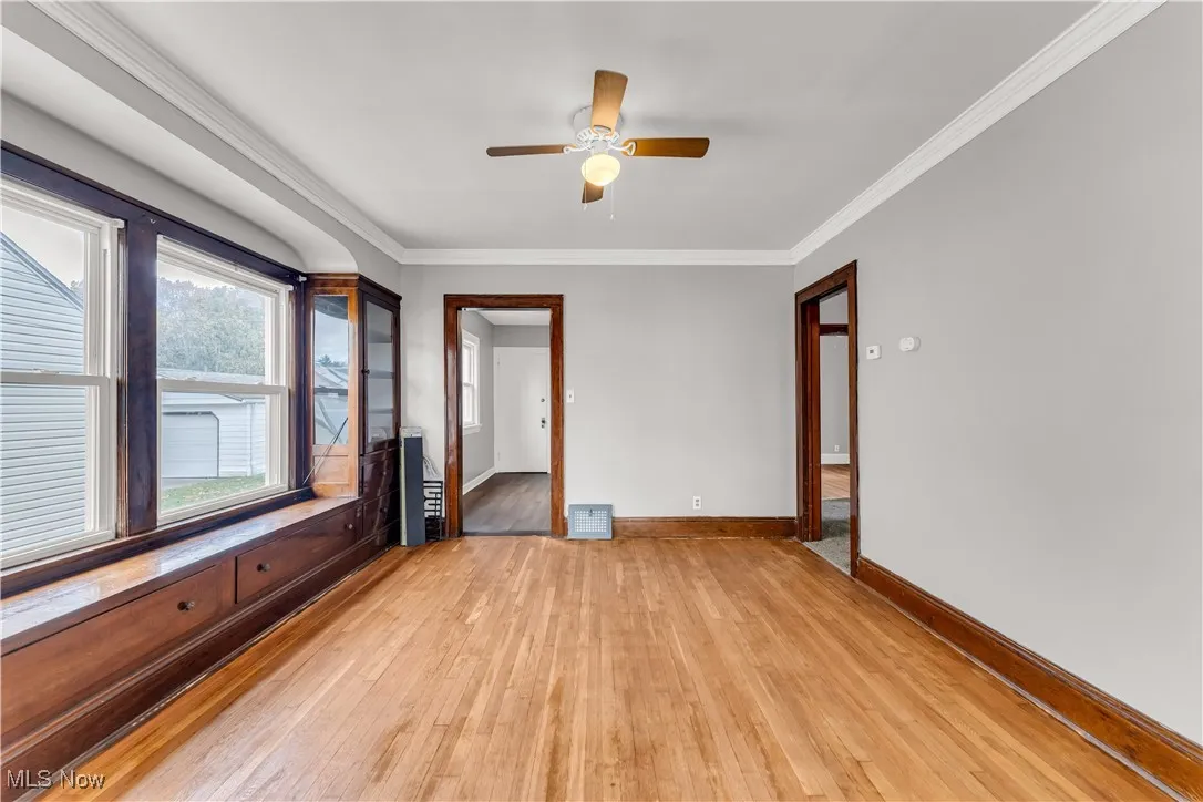 Spare room with crown molding, light wood finished floors, and ceiling fan
