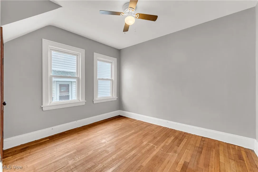 Unfurnished room with light wood finished floors, ceiling fan, and lofted ceiling