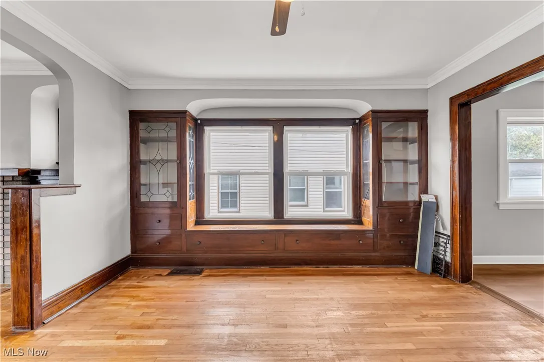 Unfurnished dining area featuring light wood-style floors, healthy amount of natural light, crown molding, and a ceiling fan