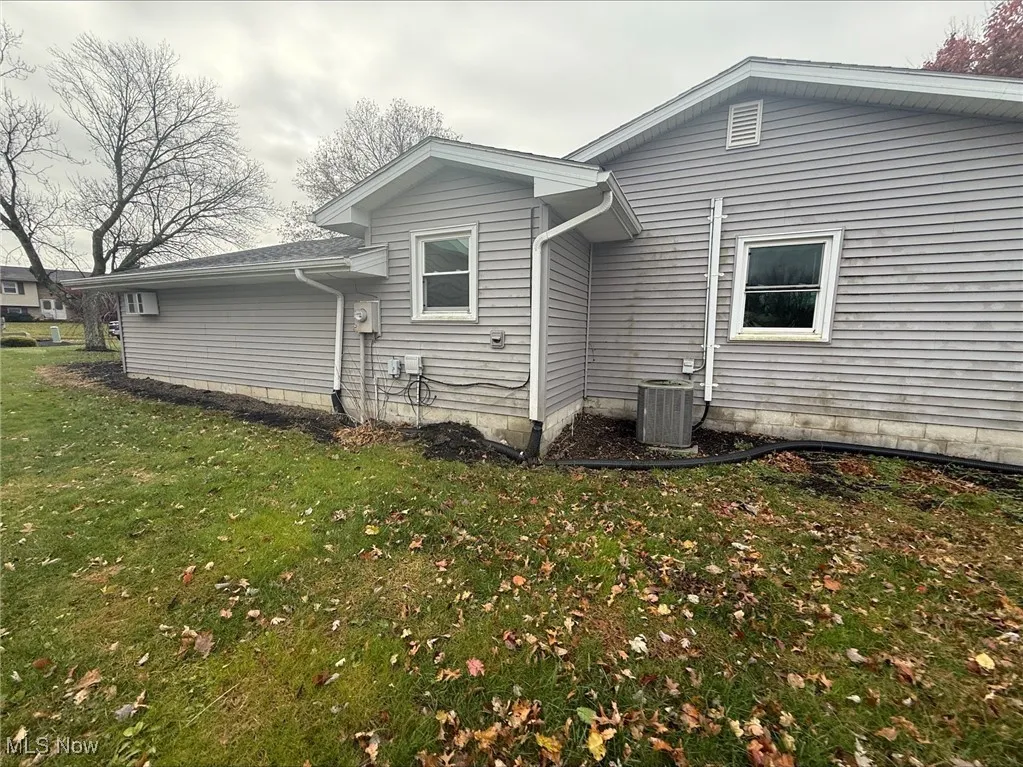 View of side of property featuring a yard and a cooling unit